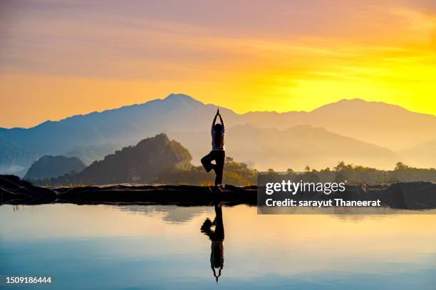 woman practicing stretching on the high mountain slopes in the morning mist and by the reflection ponds - man mist beach stock-fotos und bilder