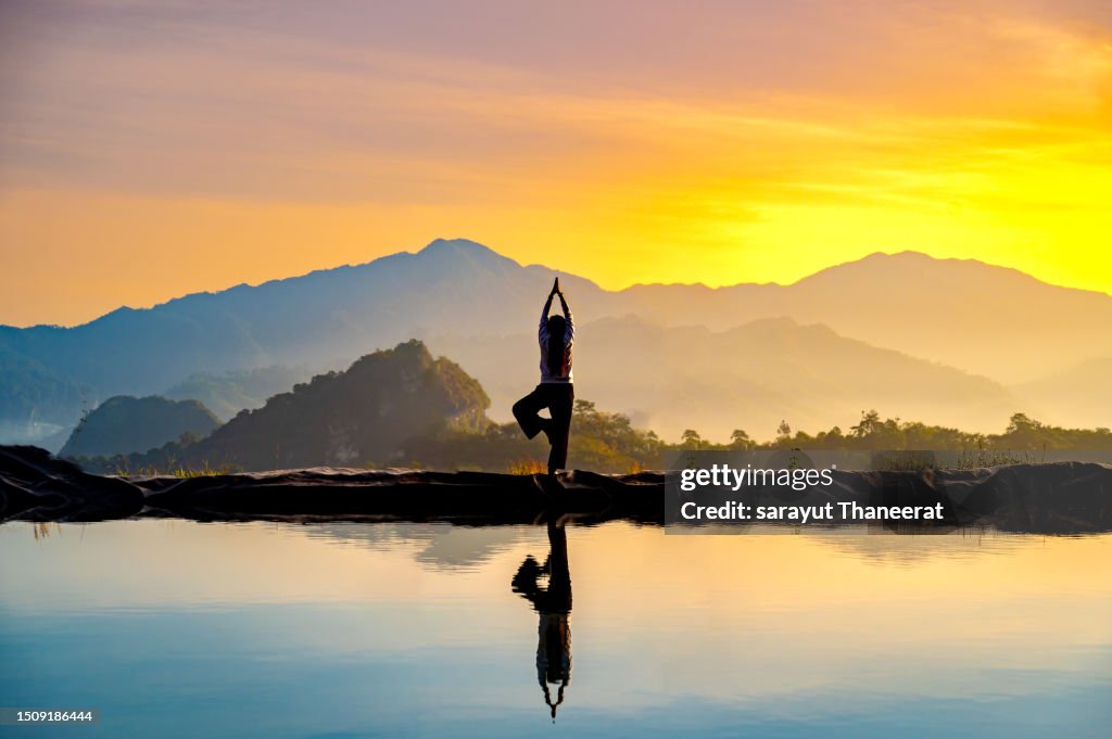 Woman practicing stretching On the high mountain slopes in the morning mist and by the reflection ponds