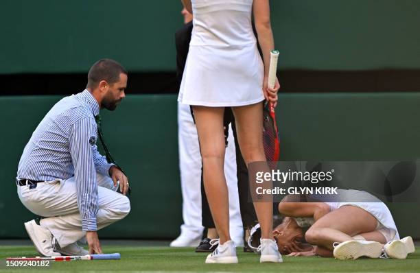 The umpire and Kazakhstan's Elena Rybakina check on France's Alize Cornet after resulting injured during their women's singles tennis match on the...