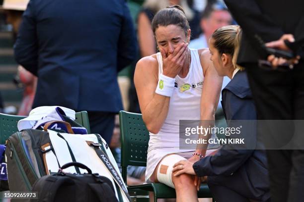 France's Alize Cornet reacts as she is tended by a physio after resulting injured during her women's singles tennis match against Kazakhstan's Elena...