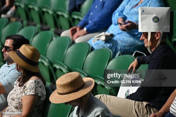 An spectator wears a paper bag on his head as a protection against the sun on the fourth day of the 2023 Wimbledon Championships at The All England...