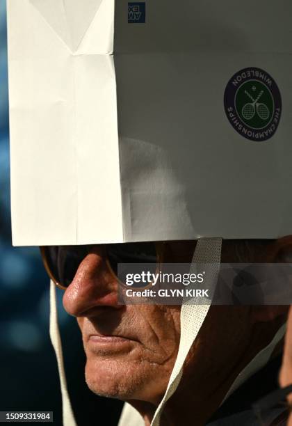 An spectator wears a paper bag on his head as a protection against the sun on the fourth day of the 2023 Wimbledon Championships at The All England...