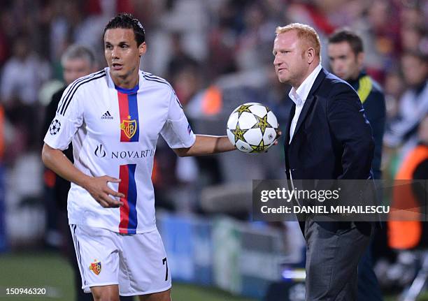 Basel's coach Heiko Vogel stands next to David Degen during their UEFA Champions League play-off second-leg football match against CFR Cluj 1907 in...