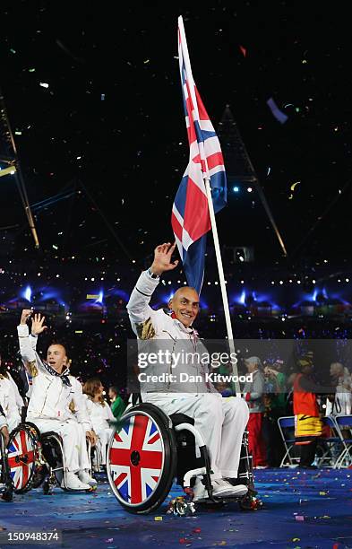 Wheelchair tennis player Peter Norfolk of Great Britain carries the flag during the Opening Ceremony of the London 2012 Paralympics at the Olympic...