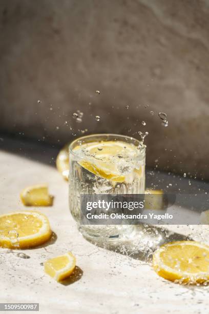 glass of water with lemon and splash - limonade stockfoto's en -beelden