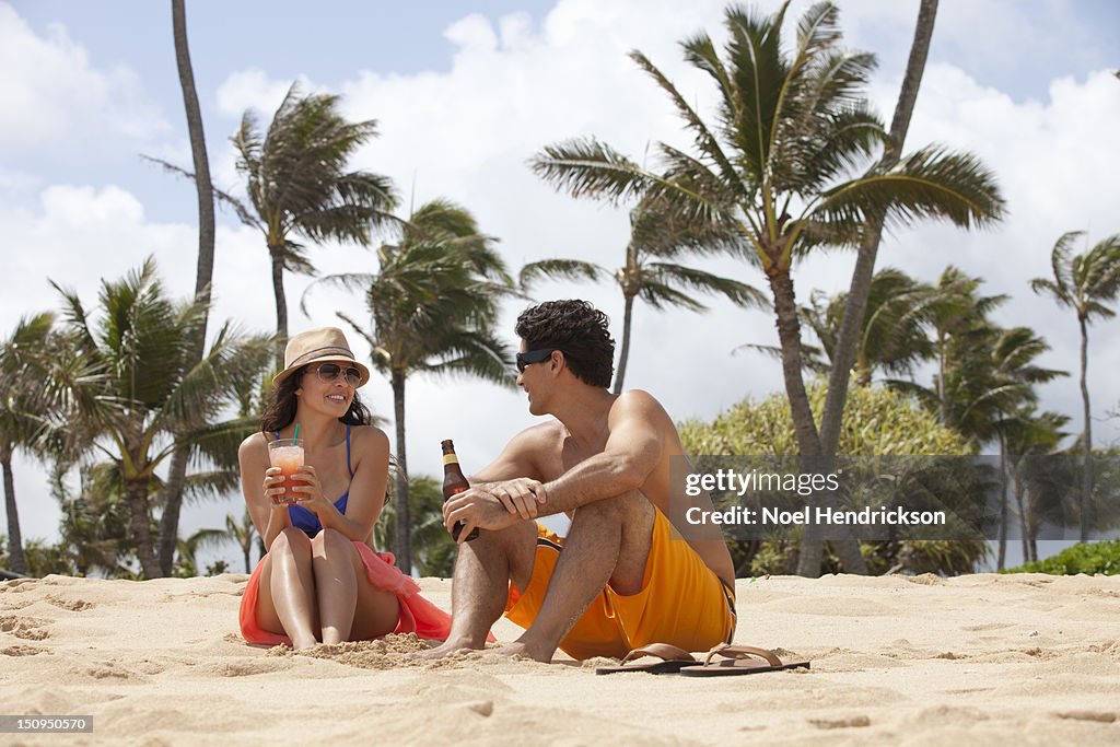 A young couple enjoys drinks on the beach