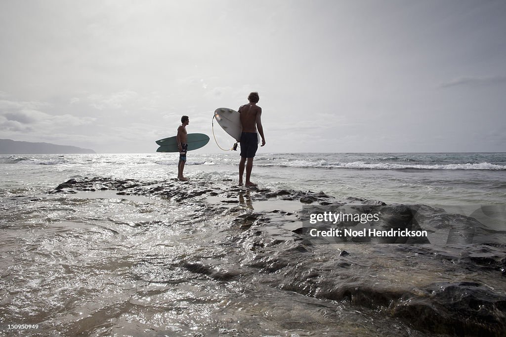 Two surfers look out at the ocean together