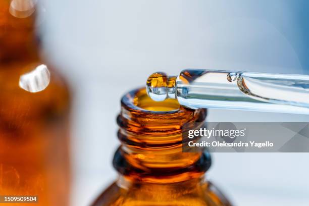 open amber bottle dropper pipette with serum or essential oil. container with cosmetic transparent liquid. - perfume lab stock pictures, royalty-free photos & images