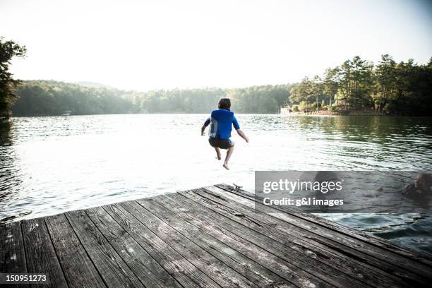 boy jumping off dock into lake - clothes on clothes off photos 個照片及圖片檔