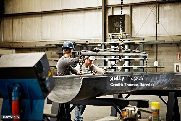 steel workers adjusting position of formed steel - steel plant stock pictures, royalty-free photos & images