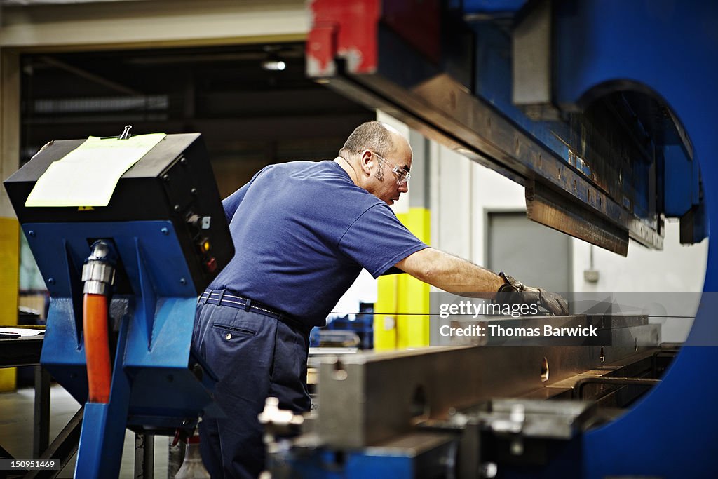 Steel worker lining up metal sheet on break press