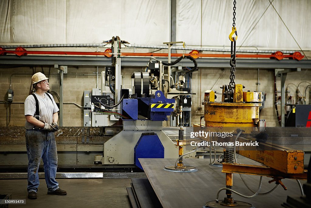 Steel worker using magnetic lift to move steel