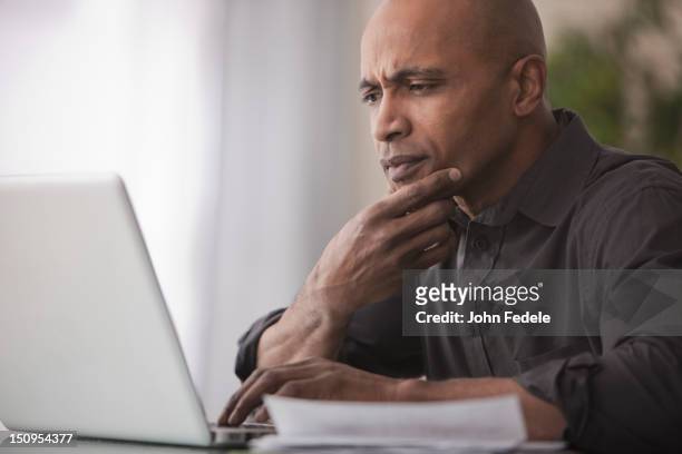 black man using laptop - uncertainty fotografías e imágenes de stock