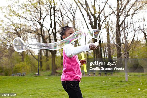 mixed race girl making bubbles in park - jamaican ethnicity imagens e fotografias de stock