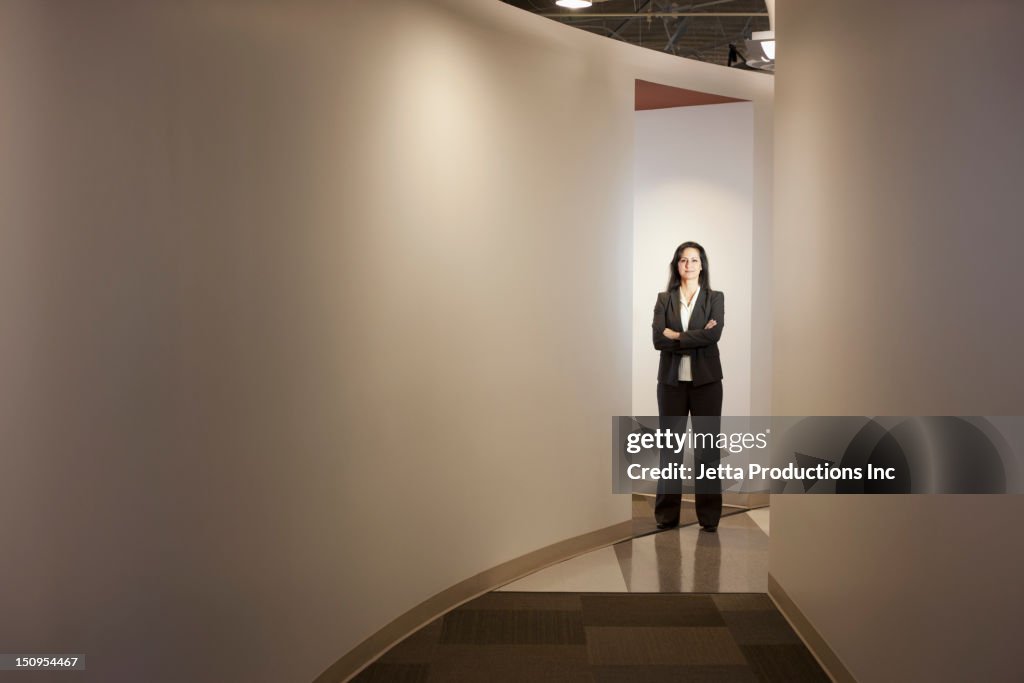 Mixed race businesswoman standing in office hallway