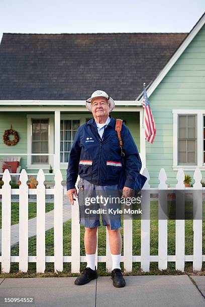 caucasian mailman standing on sidewalk - postbode stockfoto's en -beelden