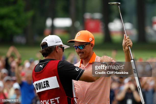 Rickie Fowler of the United States and his caddie, Ricky Romano, celebrate on the 18th green after defeating Adam Hadwin of Canada and Collin...
