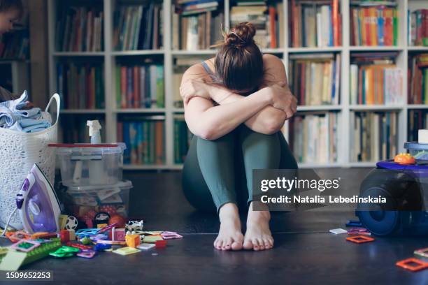 unveiling female burnout: overwhelmed woman in hunched position with vacuum cleaner and laundry basket, battling depression and everyday struggles - obsessive stockfoto's en -beelden