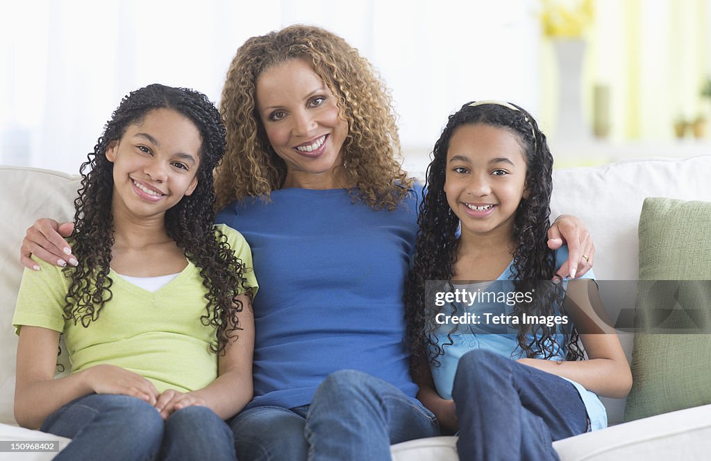 USA, New Jersey, Jersey City, Portrait of mother with daughters (10-13) sitting on sofa