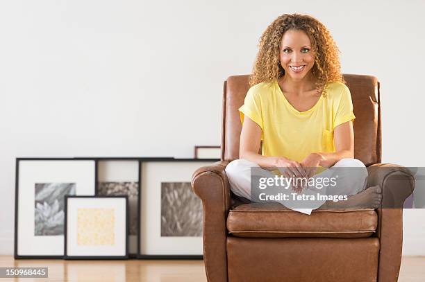 usa, new jersey, jersey city, portrait of woman sitting in armchair - schneidersitz stock-fotos und bilder