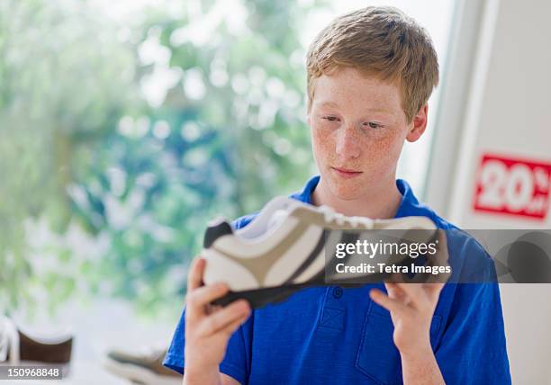 usa, new jersey, jersey city, boy (16-17) looking at shoe in shoe store - jersey city stockfoto's en -beelden