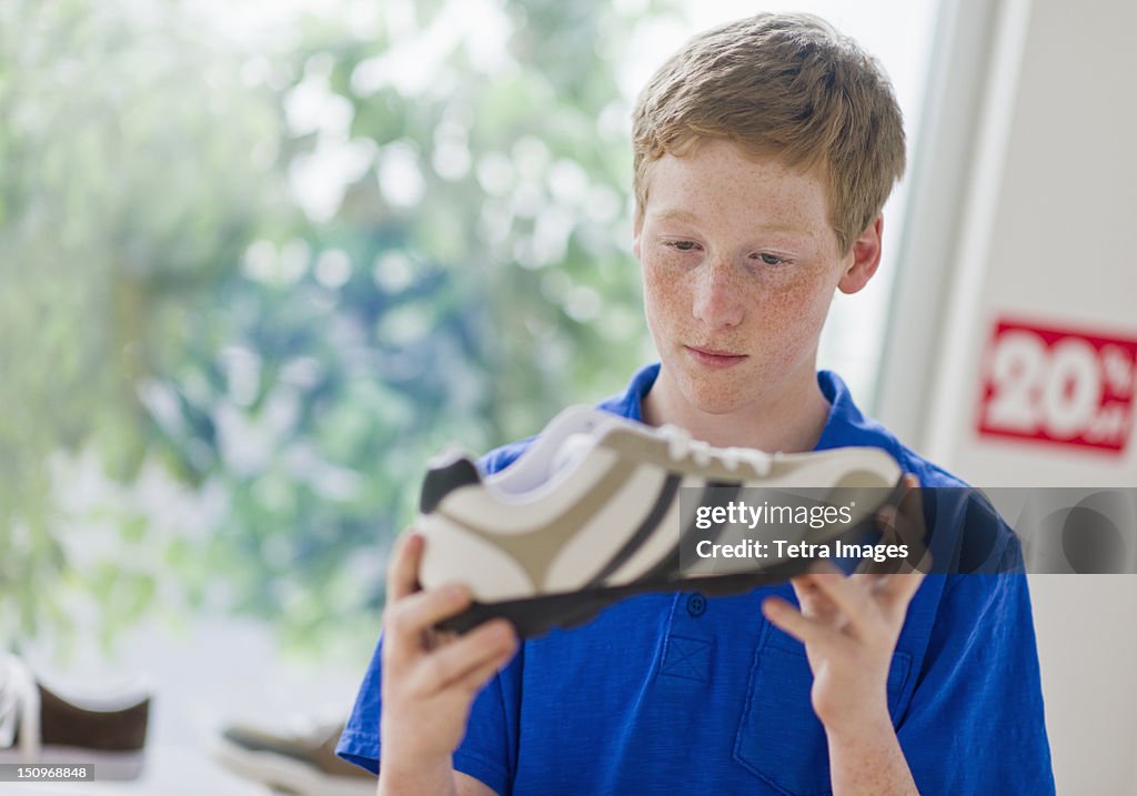 USA, New Jersey, Jersey City, Boy (16-17) looking at shoe in shoe store