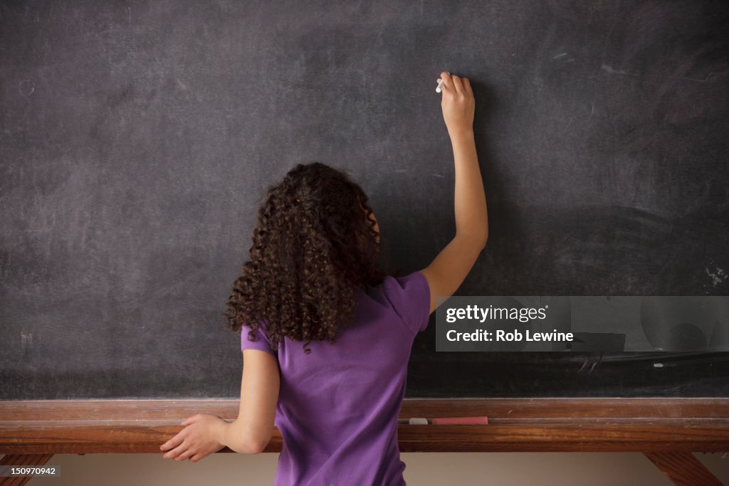 USA, California, Los Angeles, Portrait of schoolgirl (10-11) writing on blackboard