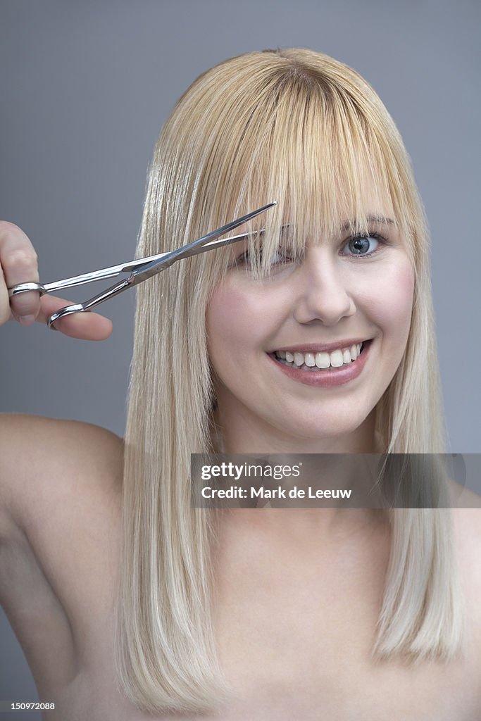 Woman cutting bangs, studio shot