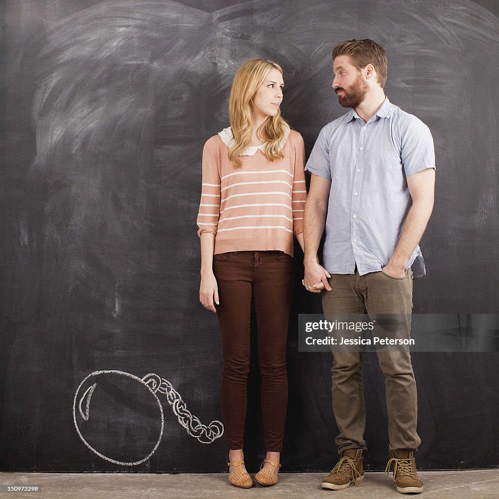 Young couple with blackboard in background, studio shot
