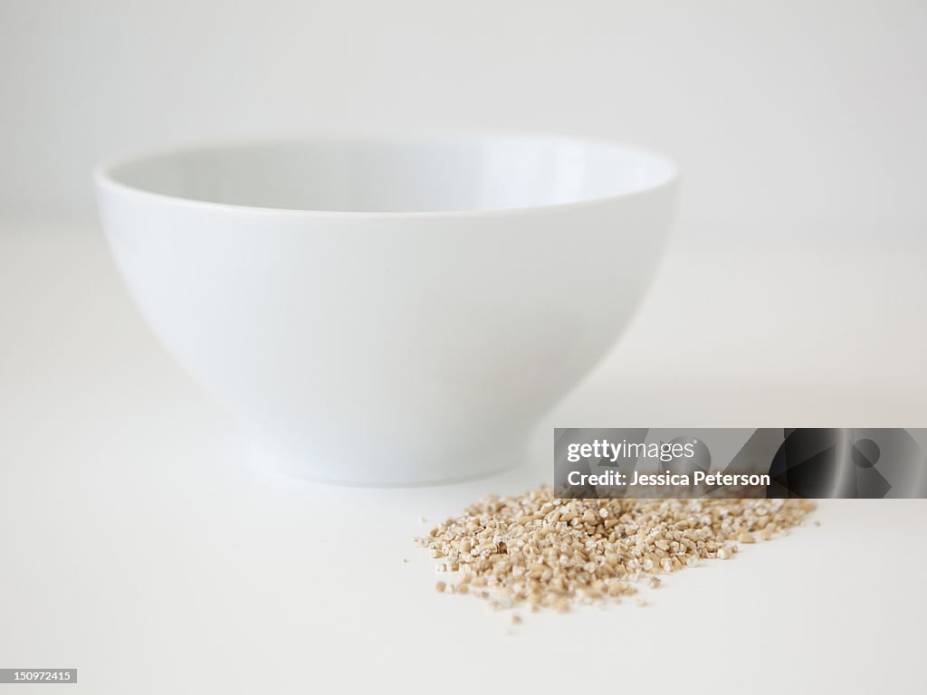 Bowl and wheat seed on white background, studio shot