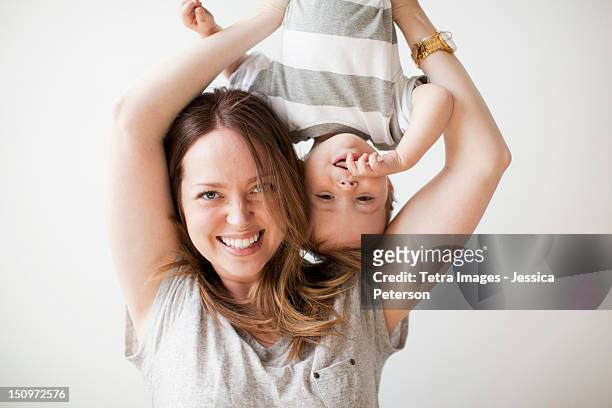 young woman holding baby boy (6-11 months) upside-down - baby studio bildbanksfoton och bilder