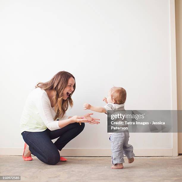 usa, utah, salt lake city, young mother assisting baby boy (6-11 months) in first steps - mother running stockfoto's en -beelden