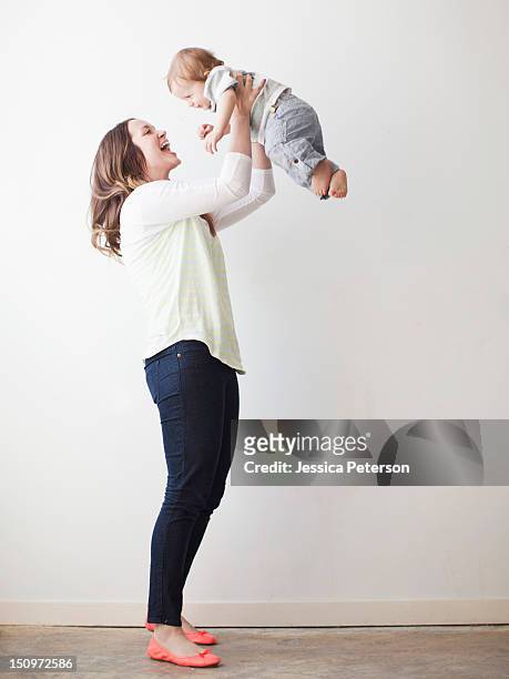 young mother lifting baby boy (6-11 months) mid-air - beautiful blonde babes stockfoto's en -beelden