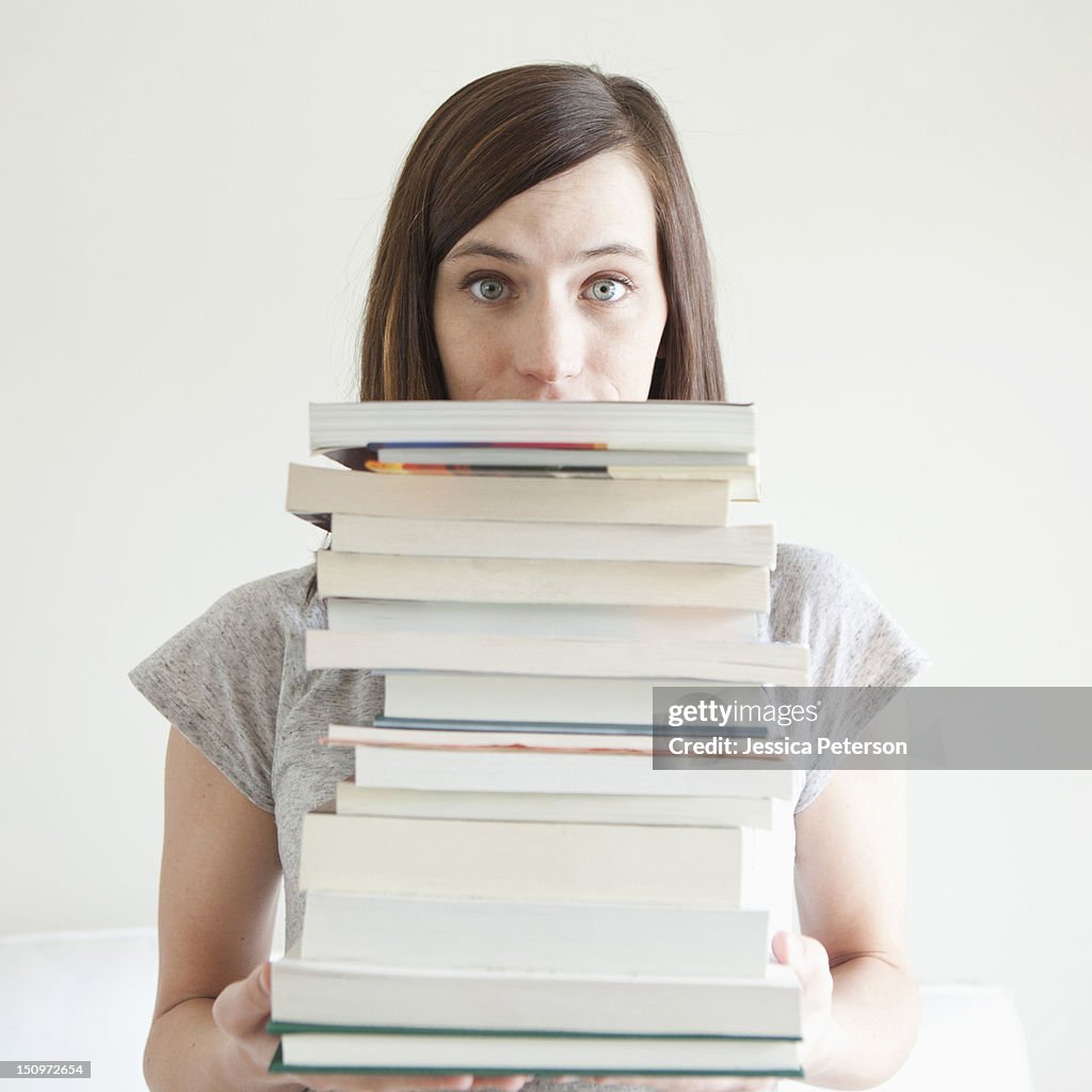 Young woman holding stack of books