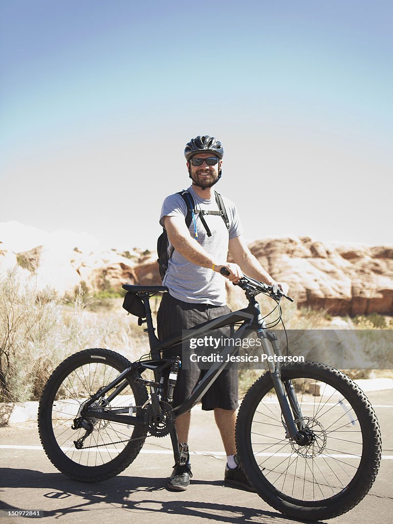 USA, Utah, Moab, Mid adult man posing with mountain bicycle in remote scenery