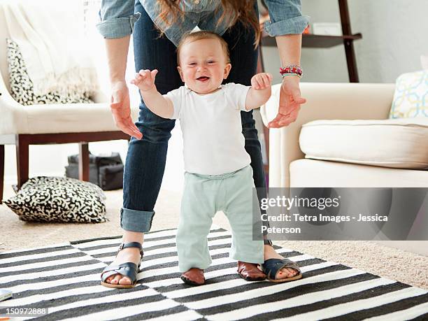 usa, utah, salt lake city, young mother assisting baby boy (6-11 months) in his first steps - first occurrence stockfoto's en -beelden