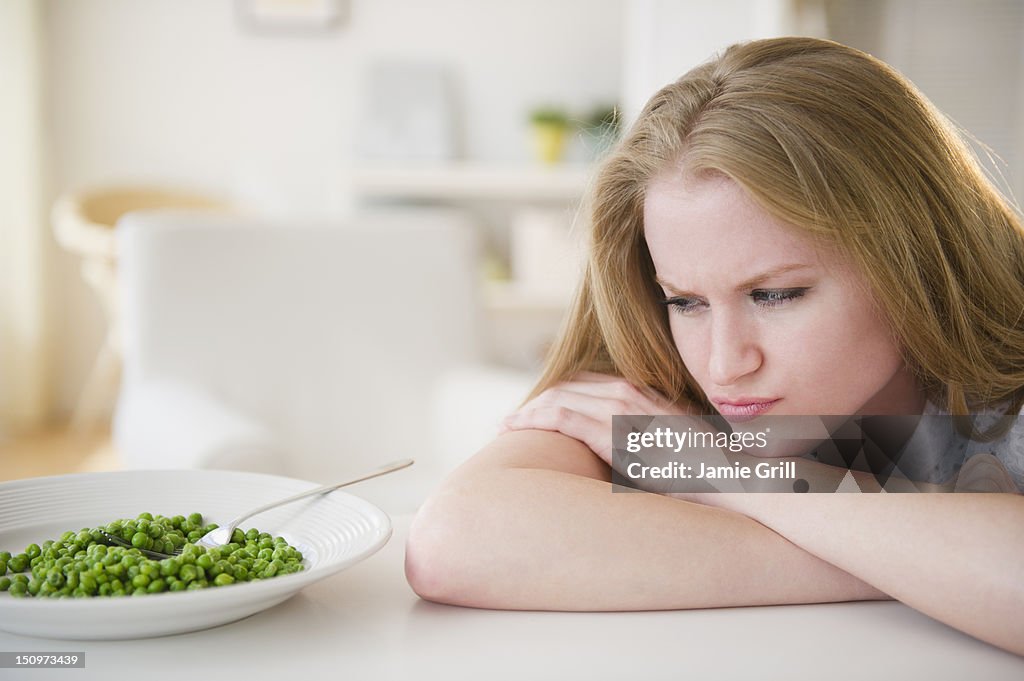 USA, New Jersey, Jersey City, Woman leaning on table looking on green peas