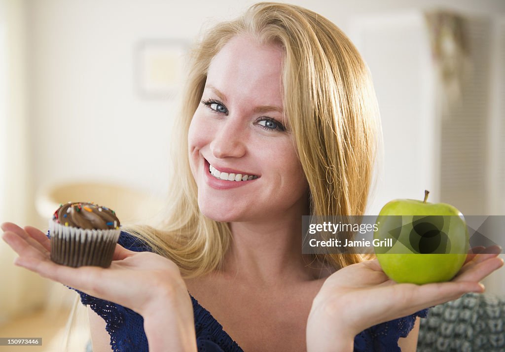 USA, New Jersey, Jersey City, Woman holding apple and cupcake