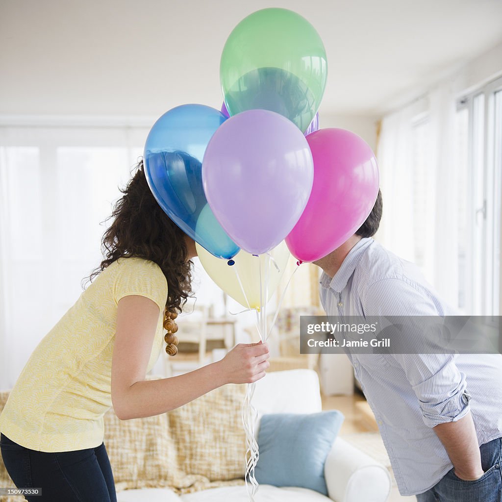 USA, New Jersey, Jersey City, Couple kissing behind bunch of colorful balloons