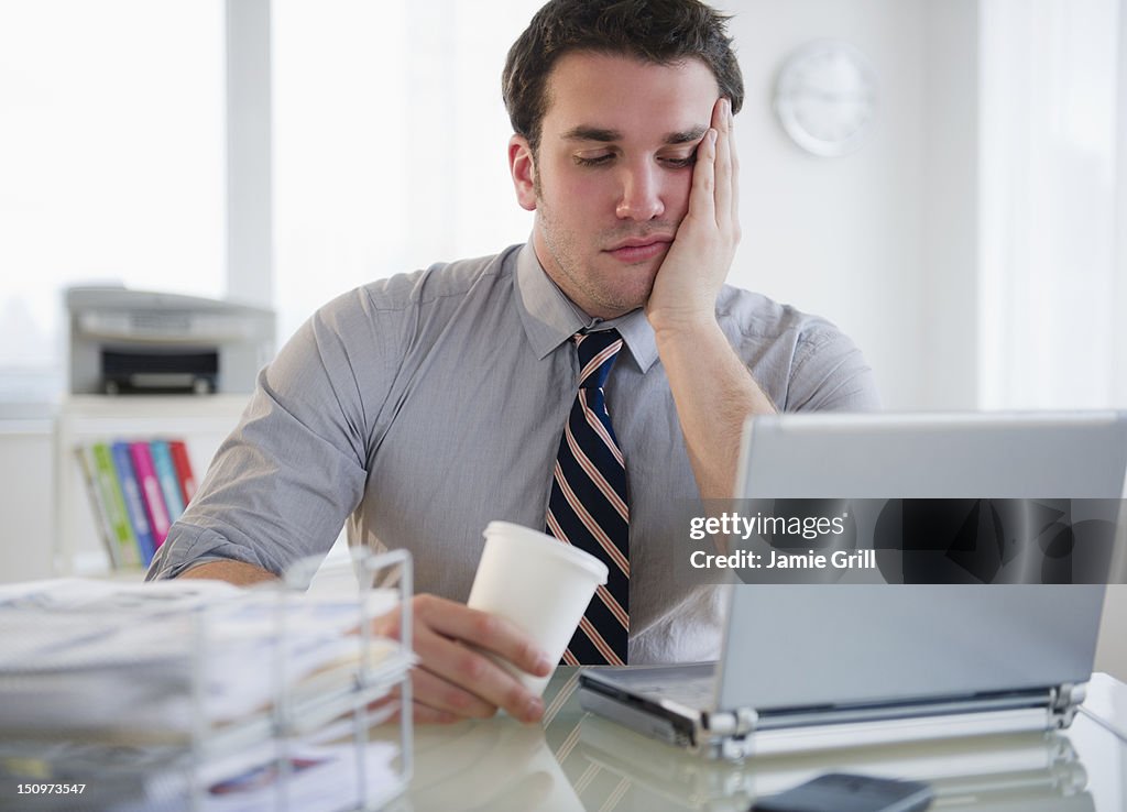 USA, New Jersey, Jersey City, Bored business man working on laptop