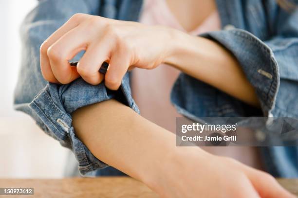 woman rolling up sleeve - rolling up sleeve stock-fotos und bilder