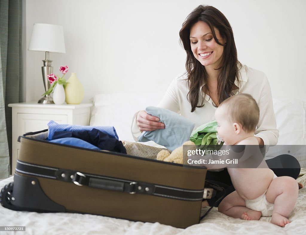 USA, New Jersey, Jersey City, Mother with baby daughter (6-11 months) packing suitcase