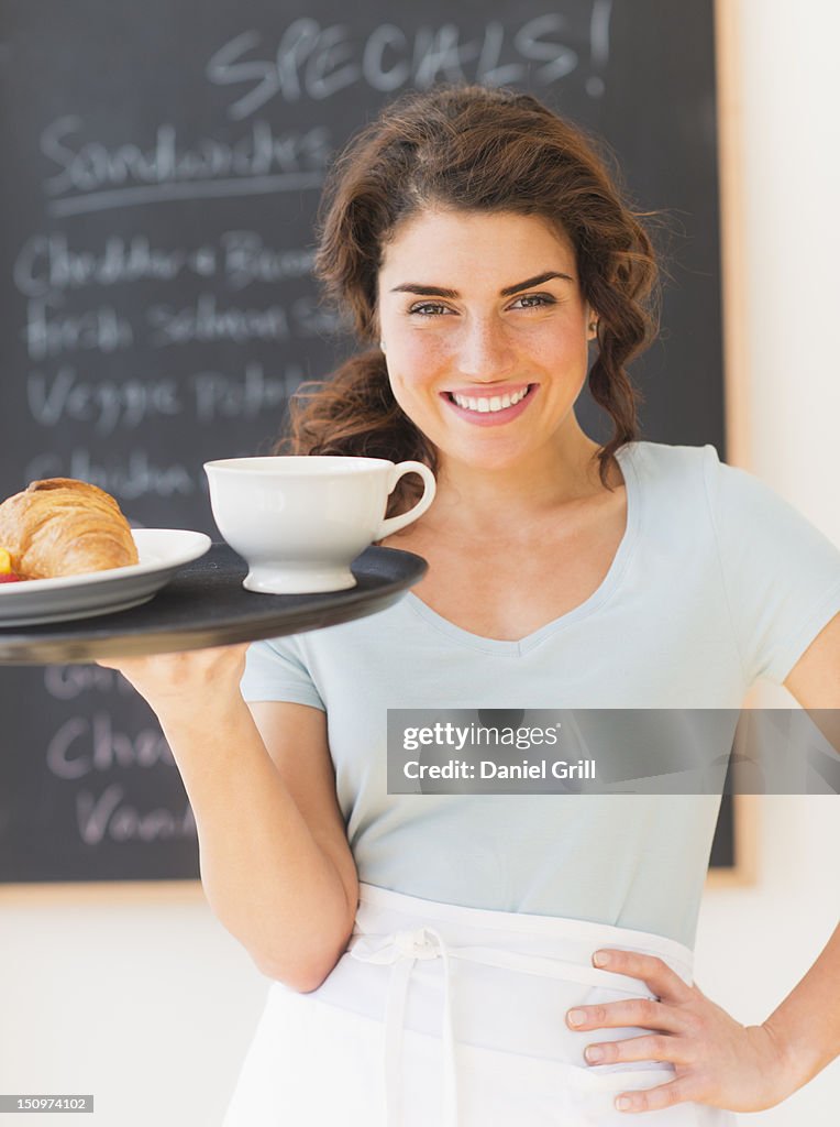 USA, New Jersey, Jersey City, Portrait of smiling waitress with tray against blackboard with menu