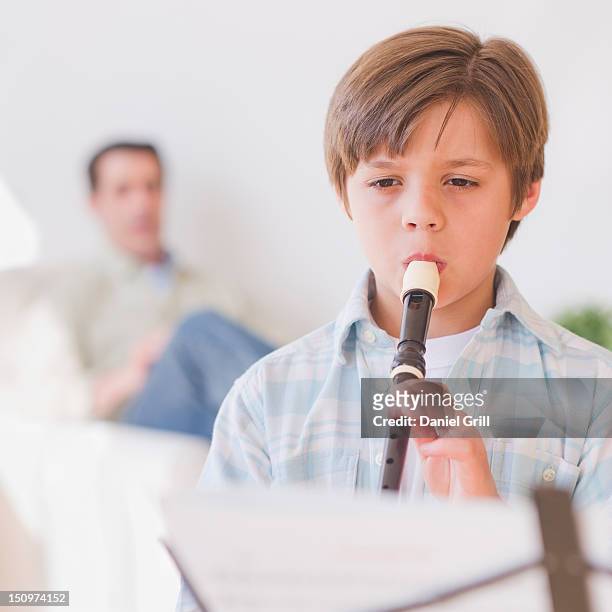 usa, new jersey, jersey city, boy (10-11 years) playing flute with father in background - 50 54 years fotografías e imágenes de stock