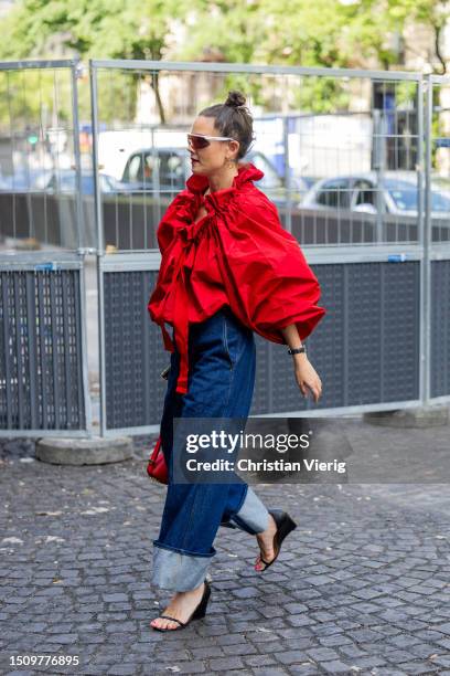 Guest wears red ruffled top, cuffed denim jeans outside Patou on July 02, 2023 in Paris, France.