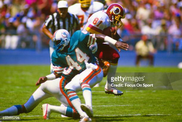 Wide Receiver Art Monk of the Washington Redskins gets rapped up from behind by a Miami Dolphins defender during an NFL football game at RFK Stadium...