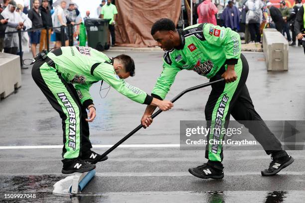Crew members of the Interstate Batteries Toyota sweep water to dry the pit area prior to the NASCAR Cup Series Grant Park 220 at the Chicago Street...