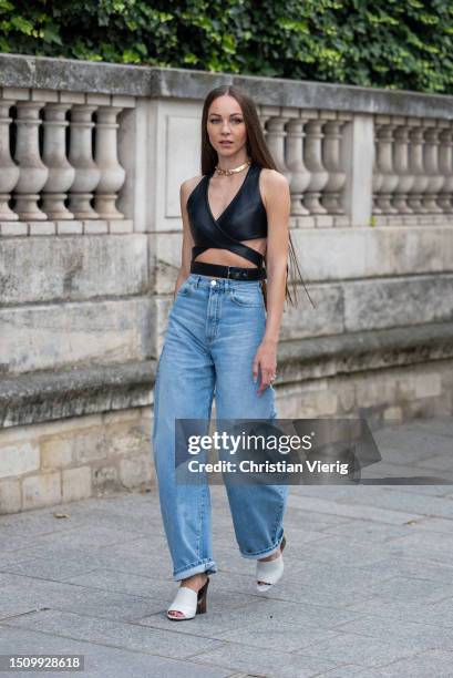 Guest wears denim jeans, black cut out top outside Alaia on July 02, 2023 in Paris, France.