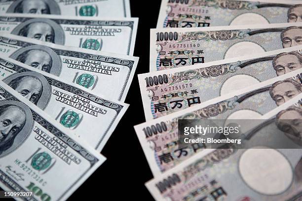 One-hundred dollar banknotes, left, and ten-thousand yen banknotes are arranged for a photograph in Soka City, Saitama Prefecture, Japan, on...