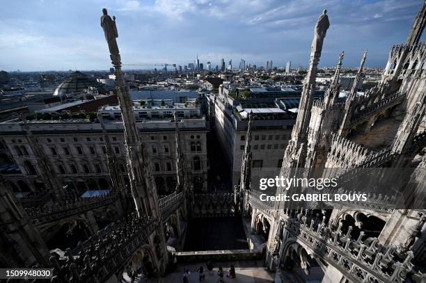 Members of the public visit the terrace of Duomo Cathedral, as the skyline of the Porta Nuova business district is seen in the background, in Milan,...